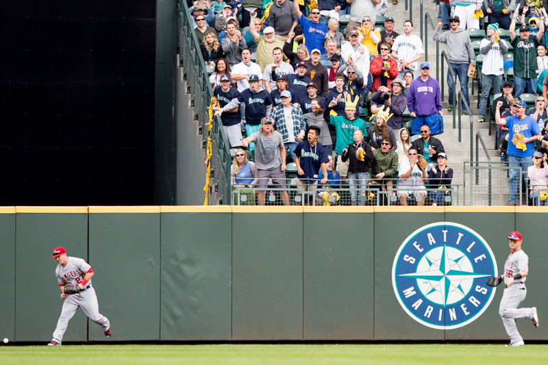 Angels outfielders bobble a deep hit to center field as Seattle fans cheer.