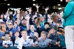 Fans reach for a baseball tossed by a player at the end of the game.