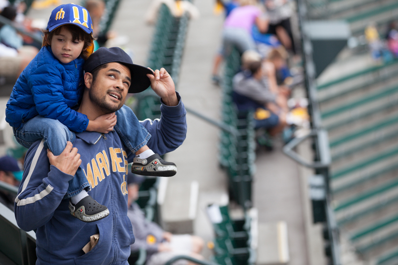 A father carries his boy to his seat as fans prepare for the Mariners' 162nd game.