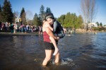 A woman carries her reluctant son out into the water for his dip.