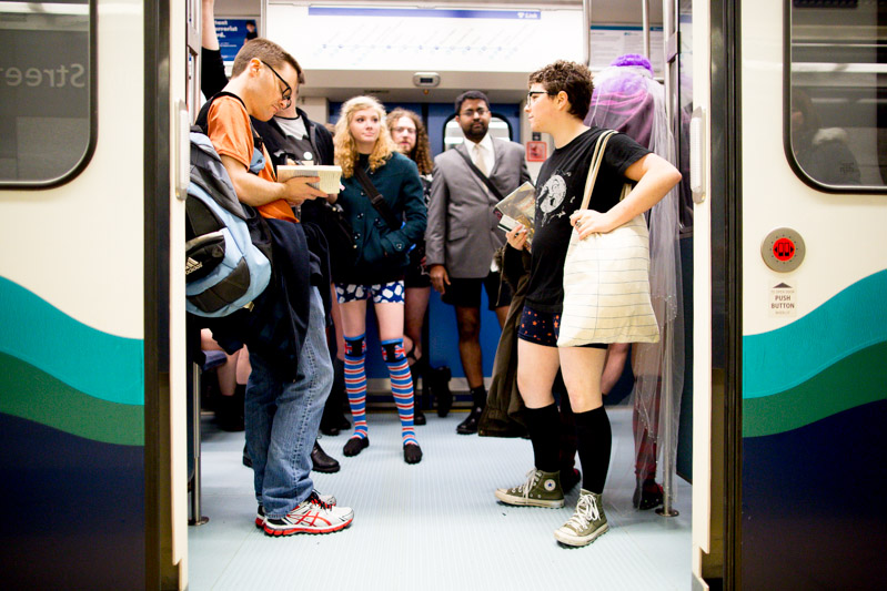 One of these folks isn't dressed like the others, as a light rail train prepares to pull away from the station.