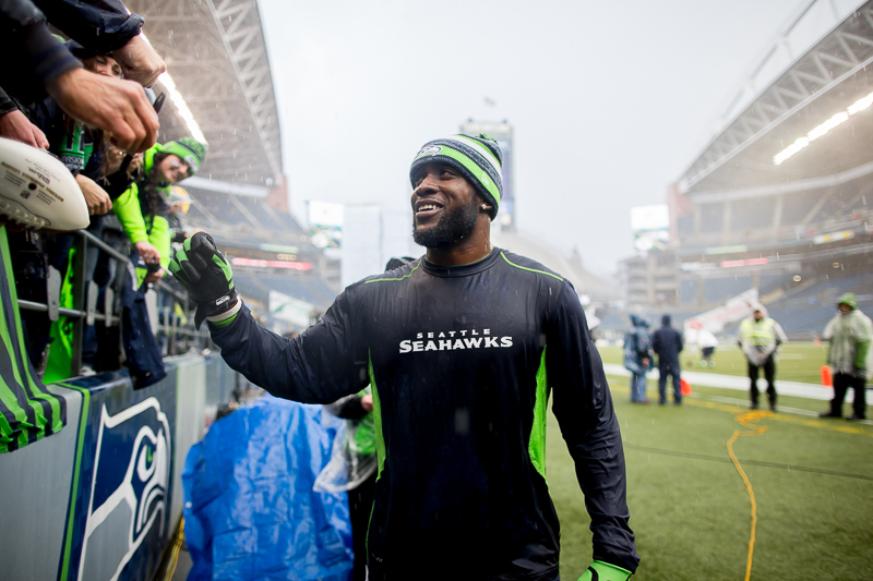 Seahawks' safety Kam Chancellor signs autographs in the pouring rain before the game.