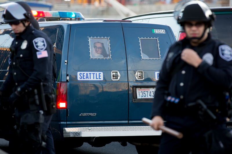 A protester glances out the rear window of a Seattle Police paddywagon.