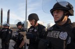 A police officer in riot gear reads a press release and list of demands put forth by the protesters.