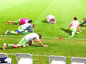 Left: Eager Sounders fans cluster behind the team’s bench. Right: pre-game stretches.
