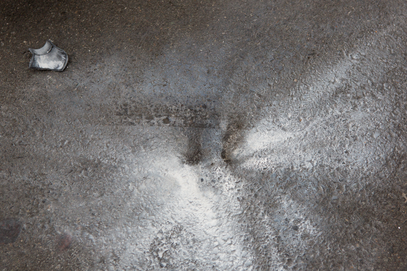 Remains from a spent flash bang shell mark the pavement.