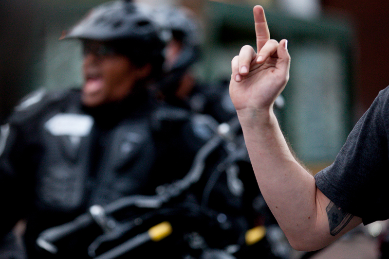 Cops receive an unambiguous gesture from a protester.