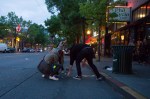 People help pick up trash from a bin overturned by protesters.