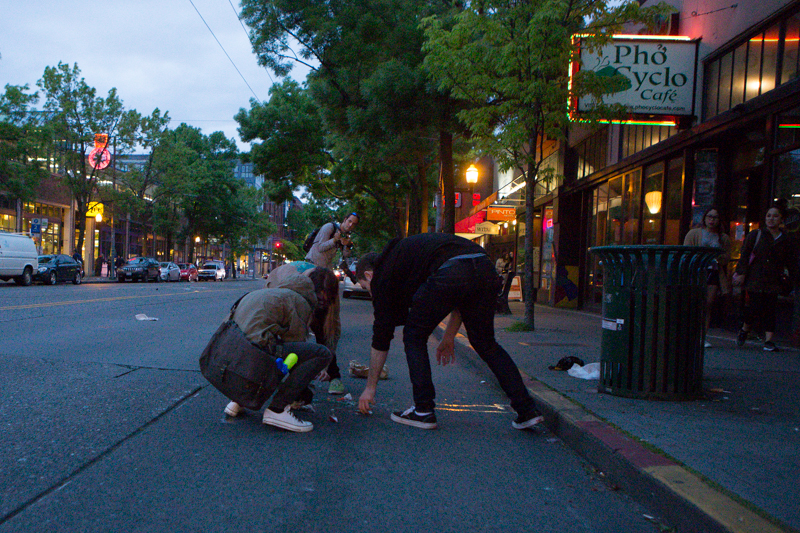 People help pick up trash from a bin overturned by protesters.