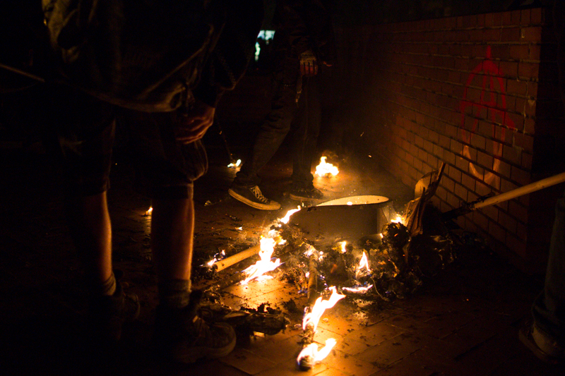 Protesters oversee the remains of a small trash bin fire on the Seattle Central campus as the event wears down.