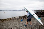 Paddleboard draped over his back, an activist makes his way to the beach to put into the water.