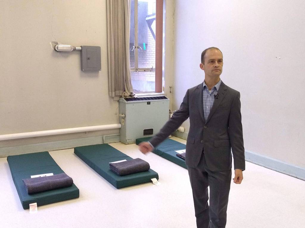 King County Housing and Community Development manager Mike Ellerbrook shows reporters sleeping mats which will be used by shelter residents until beds arrived. The Harborview Hall shelter opened on Dec. 21. Aaron Kunkler/staff photo