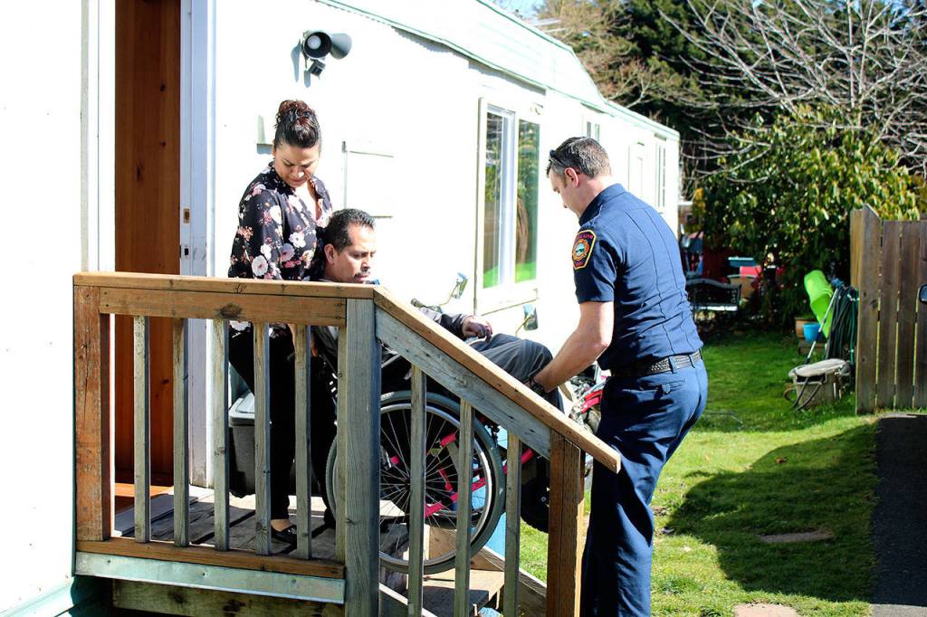 Rocio Barco (left) and SKFR PIO Brad Chaney (right) lift Bernardo Barco in his wheelchair into their non-wheelchair-accessible Des Moines home after his December 2018 motorcycle accident left him without a right arm and left leg. Haley Donwerth/ staff photo.