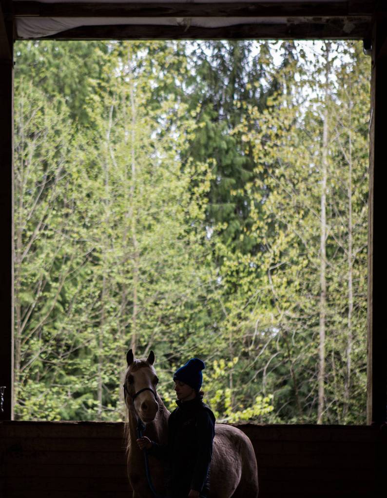 Aubrey Adler, right, and Bree stand in the arena after the end of an equine yoga class on Sunday, April 14 at Cedarbrook Veterinary Care in Snohomish. (Olivia Vanni / The Herald)