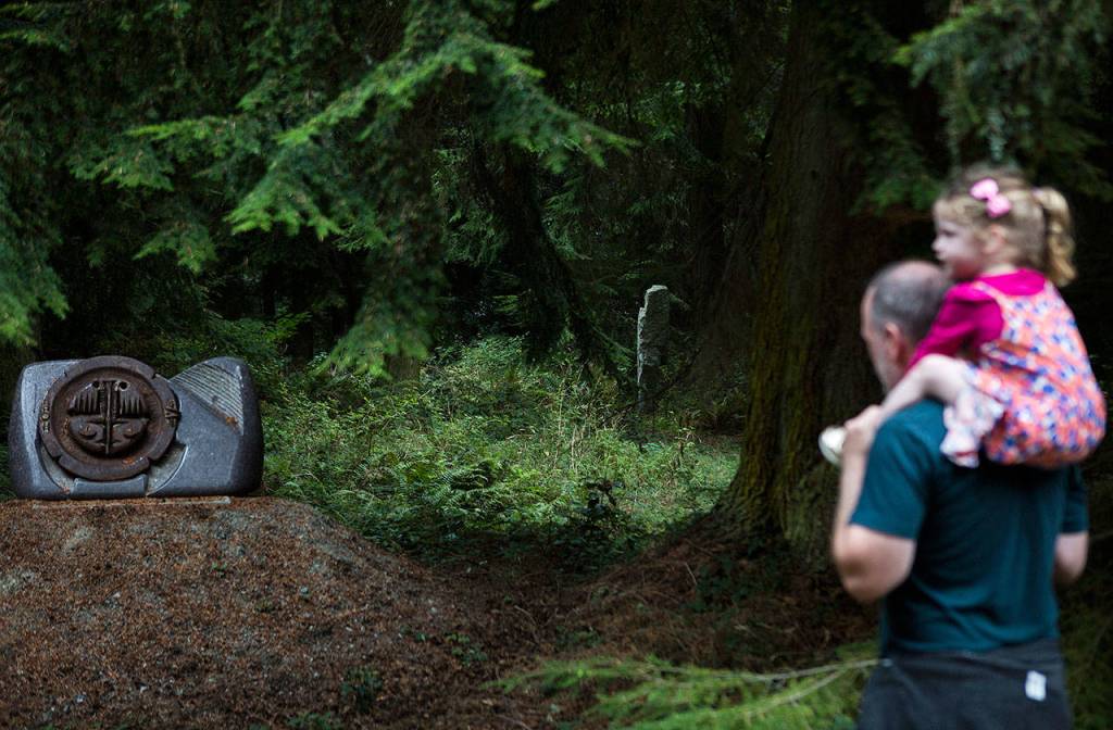 People in a tour group look and listen as two sculptures are explained at the Cloudstone outdoor gallery in Freeland. (Olivia Vanni / The Herald)
