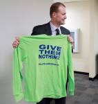 Initiative activist Tim Eyman holds a T-shirt promoting his initiative that would limit pay raises for elected officials, following his appearance in Thurston County Superior Court on Feb. 22 in Olympia. (AP Photo/Ted S. Warren, file)