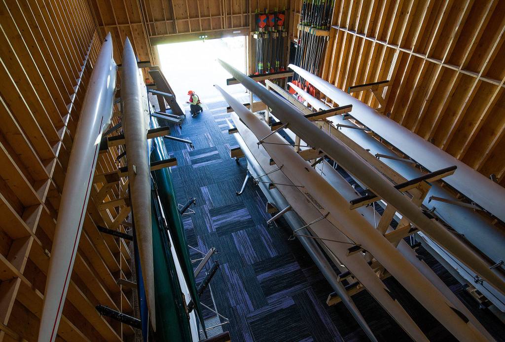 A dozen boats await their crews as North Cascade Crew volunteer coach Catherine Runyon writes down assignments in the new Joe Rantz Boathouse on Tuesday in Lake Stevens. (Andy Bronson / The Herald)