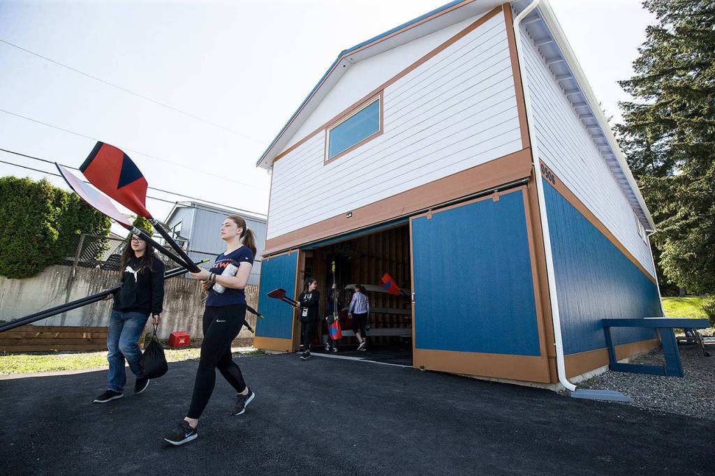 North Cascade Crew members carry oars to Lake Stevens from the new Joe Rantz Boathouse on Tuesday in Lake Stevens. (Andy Bronson / The Herald)