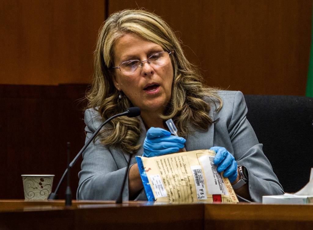 Lisa Collins, a forensic scientist with the Washington State Patrol, looks at a swab used to collect DNA from William Talbott II during the trial of William Talbott II at the Snohomish County Courthouse on Monday in Everett. (Olivia Vanni / The Herald)