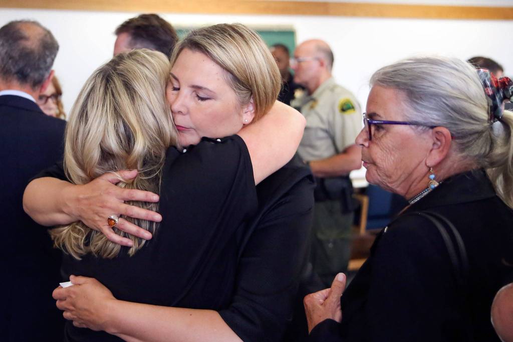 May Robson gets a hug from Kelly Cook with Lee Cook (right) after the guilty verdict of William Talbott II Friday morning at the Snohomish County Court House in Everett on June 28, 2019. Talbott was found guilty of all charges. (Kevin Clark / The Herald)