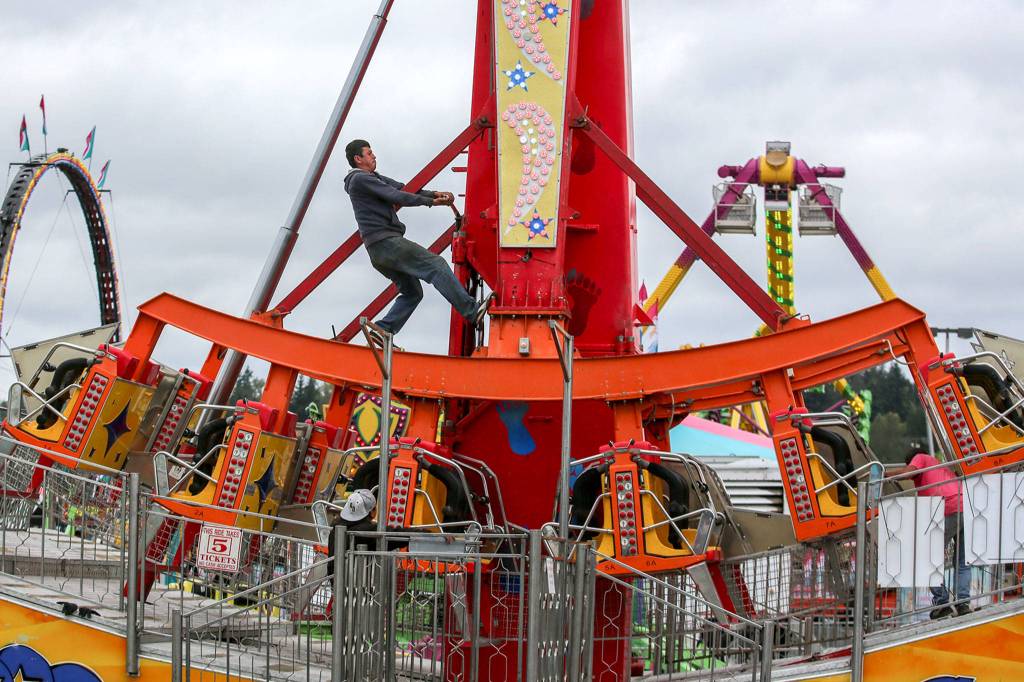 A crew member works to set up a ride Wednesday afternoon at the Evergreen State Fairgrounds. (Kevin Clark / The Herald)