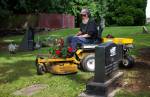 Cliff Edwards, 65, the sexton at Edmonds Memorial Cemetery & Columbarium, picks up and carries memorial flowers on his mower as he cuts the grass around headstones on Monday in Edmonds. (Andy Bronson / The Herald)