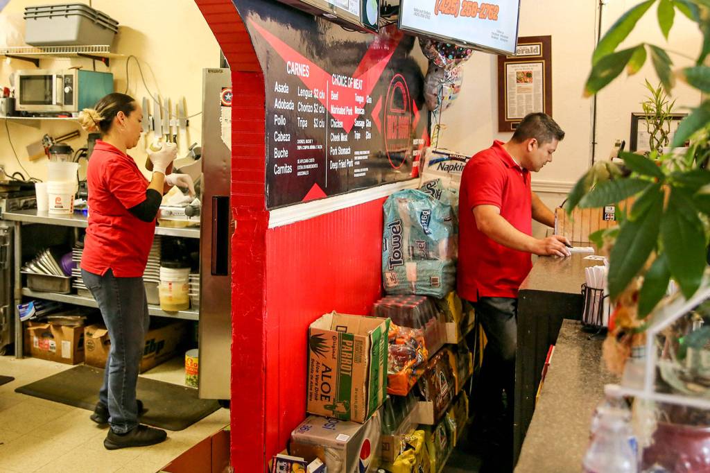 Deisy Ramos cooks in the back and her husband, Rigoberto Bastida, takes orders at their restaurant, Taco-Book, in Everett. (Kevin Clark / The Herald)