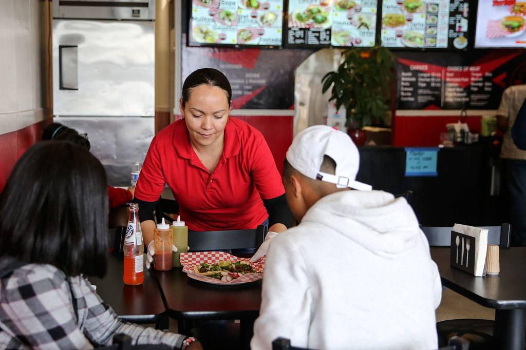 Deisy Ramos delivers food to customers at Taco-Book in Everett. (Kevin Clark / The Herald)