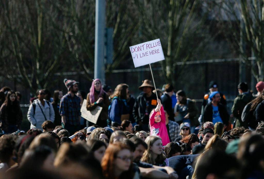 A young girl holds up a Dont Pollute I Live Here sign in the crowd during the Youth Climate Strike at Cal Anderson Park on Friday, March 15, 2019 in Seattle, Wash. (Olivia Vanni / The Herald)