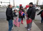Vincent Grieci offers his hat to Vili Bloomfield, the son of Samiu Bloomfield, as friends and fans gather on Broadway to wave in honor of Samiu on Monday in Everett. Bloomfield , who died Sunday, was known for waving the American flag and the tattoos that covered his face and body. (Andy Bronson / The Herald)