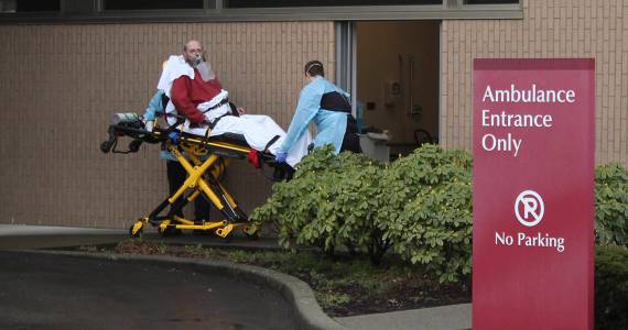 At St. Elizabeth Hospital in Enumclaw, a patient is taken from an ambulance through a small door marked decontamination on March 23. It was unclear whether the patient was suspected of being infected with COVID-19. (Photo by Ray Miller-Still/Sound Publishing)