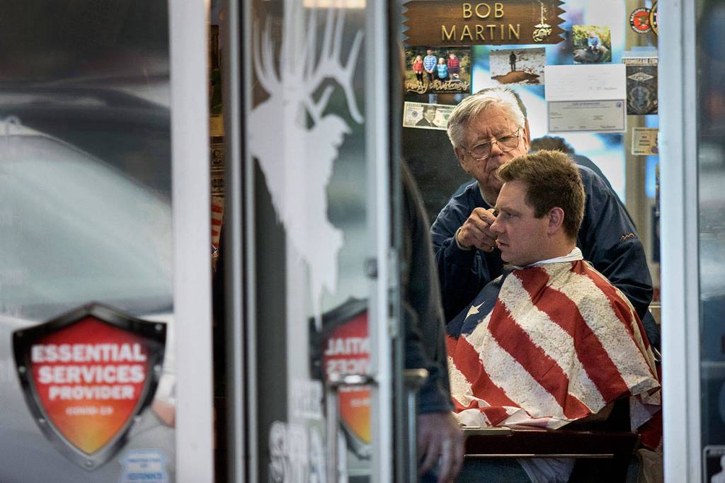 In defiance of Gov. Jay Inslees stay-home order, owner Bob Martin cuts a customers hair at The Stag barbershop on Saturday, May 2, 2020, in Snohomish, Wash. Dozens of people showed up and stood in line to get a haircut. Photo by Andy Bronson/The Herald