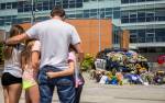 Ryan Murphy holds his daughters, Peyton, Teegan and Paisley, as they pay their respects Tuesday to the Bothell police officer who was killed Monday night. (Olivia Vanni / The Herald)