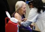 Jackie Hoernor, a resident at South Pointe Assisted Living, winces as she gets her Pfizer COVID-19 vaccination during a Walgreens Vaccine Clinic at South Pointe on Feb. 12 in Everett. (Olivia Vanni / The Herald)