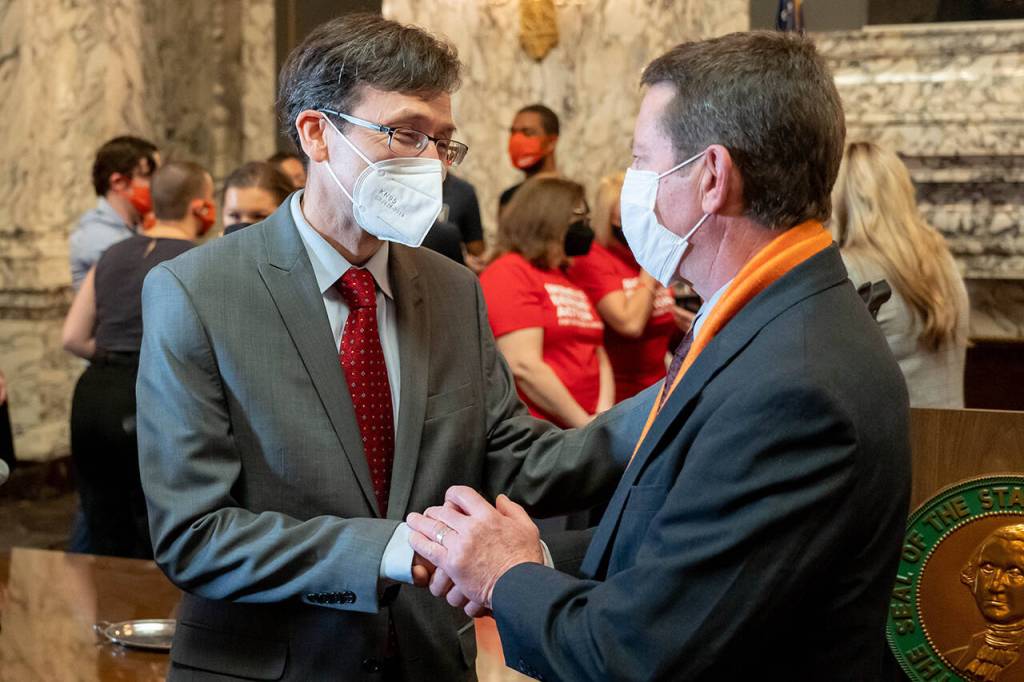 Washington Attorney General Bob Ferguson (left) speaks with Paul Kramer at the signing of bills aimed at reducing gun violence Wednesday in Olympia. Kramers son Will was injured in a 2016 mass shooting in Mukilteo that left three people dead. (Washington State Attorney General)