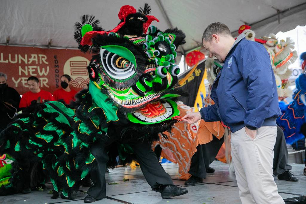 Photo by Ryan Berry / The Herald
Edmonds Mayor Mike Nelson rewards a lion dancer with a traditional red envelope during a celebration of the Lunar New Year on Saturday, Jan. 21, 2023.